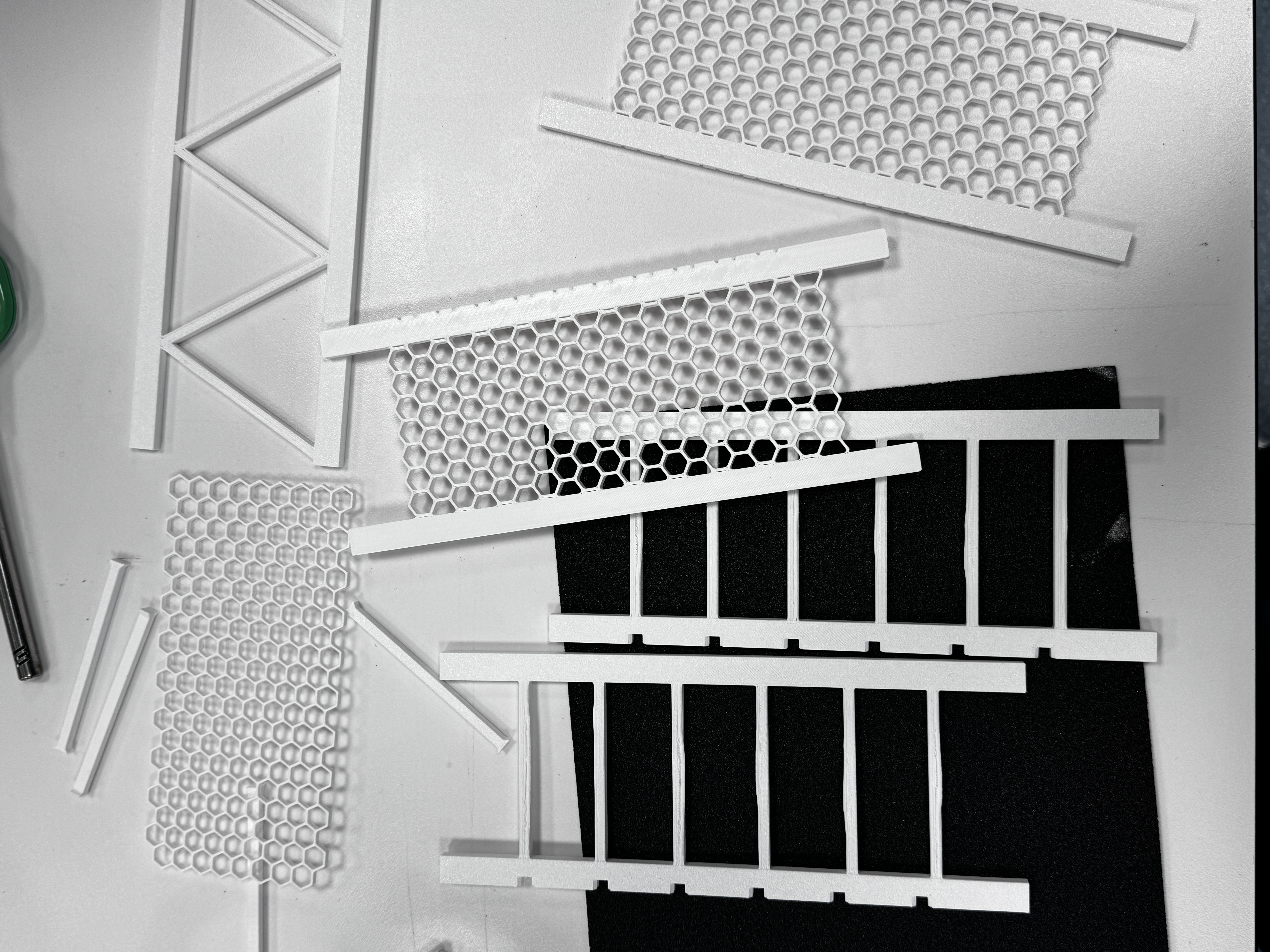 Multiple 3D-printed lattice bridge components laid out showing surface variation